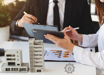 Real estate professionals reviewing financial charts with model buildings on the table, discussing investment opportunities